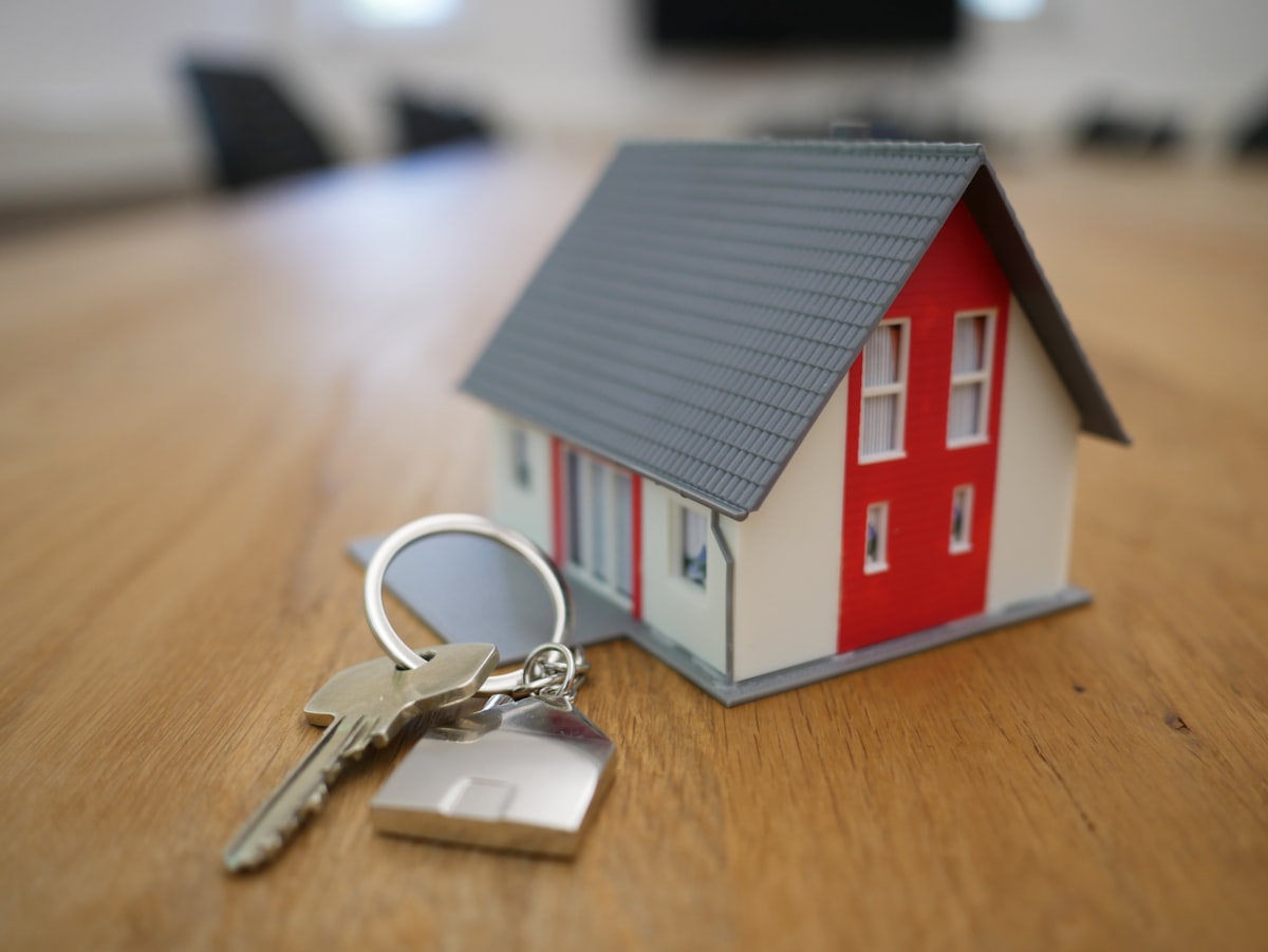 Hands holding house keys and a small model home